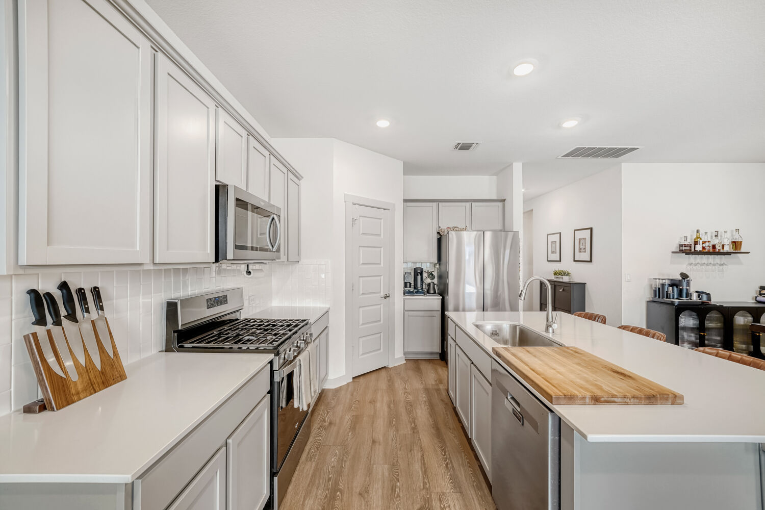 2308 Ranier Court Austin, TX 78754 - Photo 12 of 29 Kitchen with stainless steel appliances, a center island with sink, light wood-type flooring, backsplash, and recessed lighting