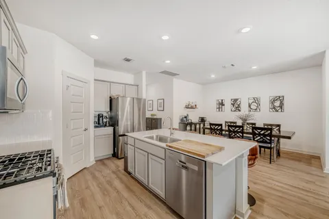 a kitchen with a sink a stove a refrigerator and chairs