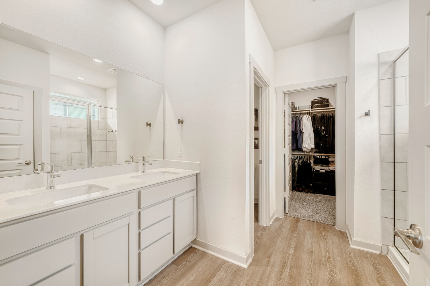 2308 Ranier Court Austin, TX 78754 - Photo 19 of 29 Full bathroom featuring a shower stall, double vanity, light wood-type flooring, and a spacious closet
