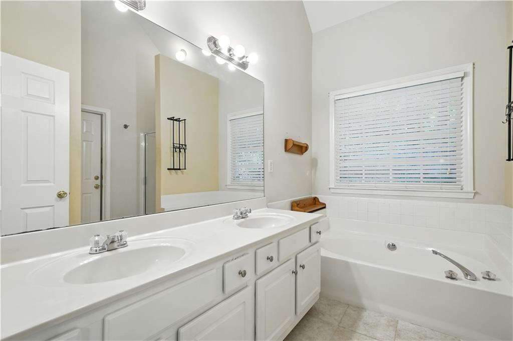 6745 Fairfield Trace Suwanee, GA 30024 - Photo 19 of 37 a bathroom with a tub a sink double vanity and a mirror