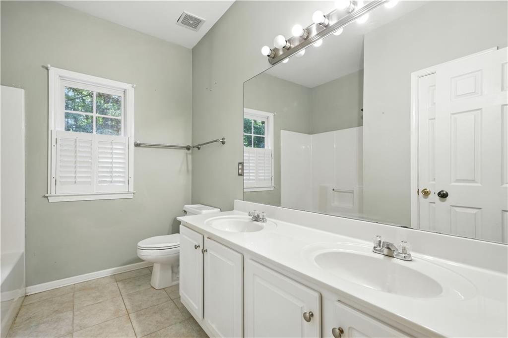 6745 Fairfield Trace Suwanee, GA 30024 - Photo 23 of 37 a bathroom with a toilet a sink and mirror