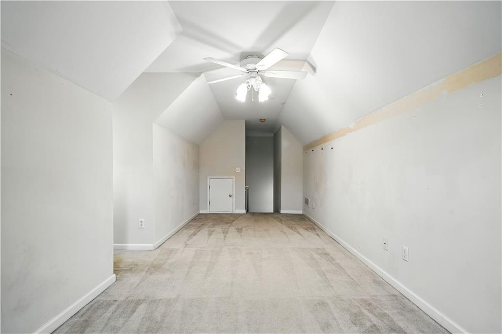 6745 Fairfield Trace Suwanee, GA 30024 - Photo 28 of 37 an empty room with a chandelier fan and wooden floor