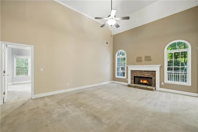 an empty room with windows a fireplace a ceiling fan and a fireplace