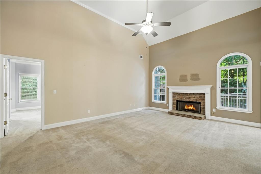 6745 Fairfield Trace Suwanee, GA 30024 - Photo 7 of 37 an empty room with windows a fireplace a ceiling fan and a fireplace