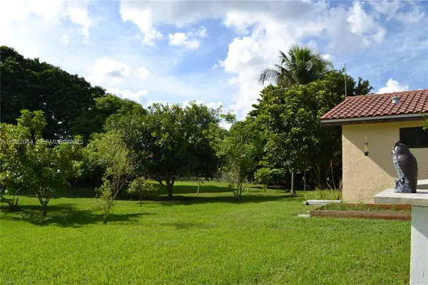 a kitchen with stainless steel appliances granite countertop a refrigerator a sink a stove a dining table and chairs with wooden floor