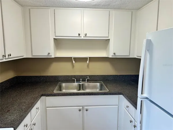 a kitchen with granite countertop white cabinets and a sink