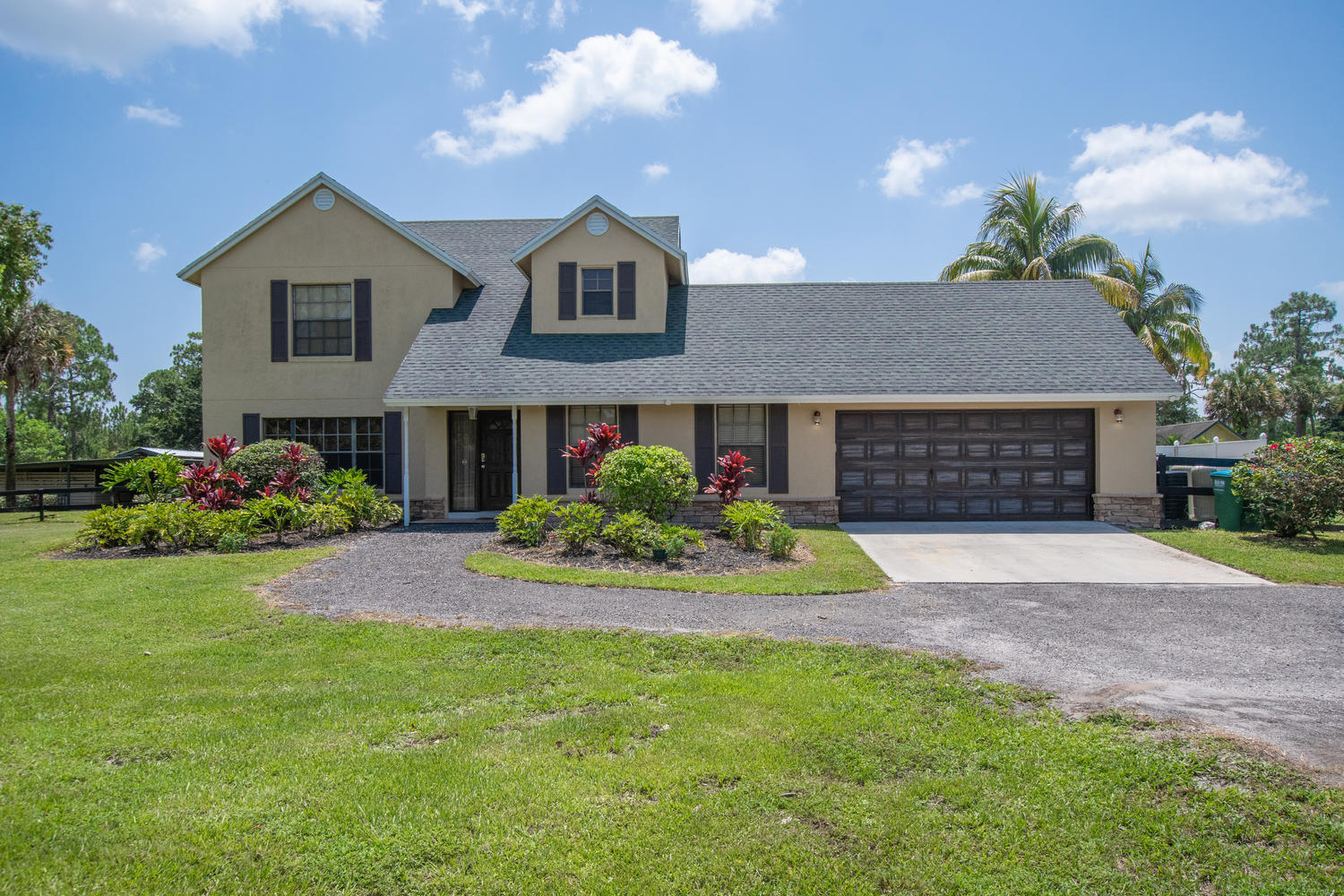 1350 C Road Loxahatchee Groves, FL 33470 - Photo 1 of 27 a front view of a house with a garden and plants