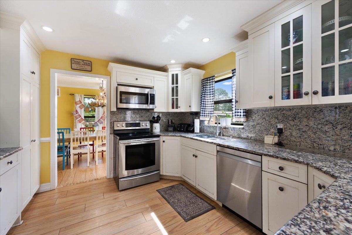 1350 C Road Loxahatchee Groves, FL 33470 - Photo 3 of 27 a kitchen with stainless steel appliances granite countertop a stove top oven a sink dishwasher a refrigerator and a microwave oven with wooden floor
