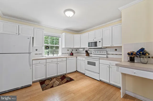 a kitchen with white cabinets white appliances and sink