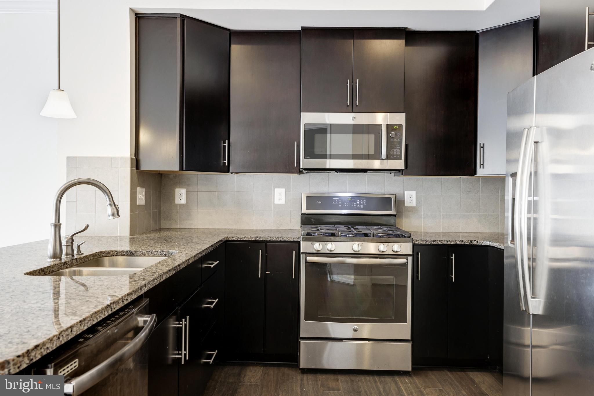 13660 Endeavour Drive, Unit 20C Herndon, VA 20171 - Photo 10 of 35 a kitchen with granite countertop a stove and a refrigerator