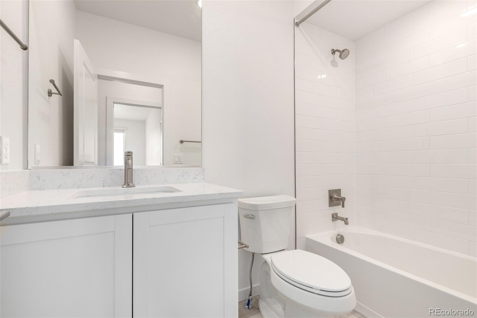 6153 North Ceylon Street, Unit 303 Denver, CO 80249 - Photo 19 of 22 a bathroom with a toilet a sink a mirror a bathtub and vanity