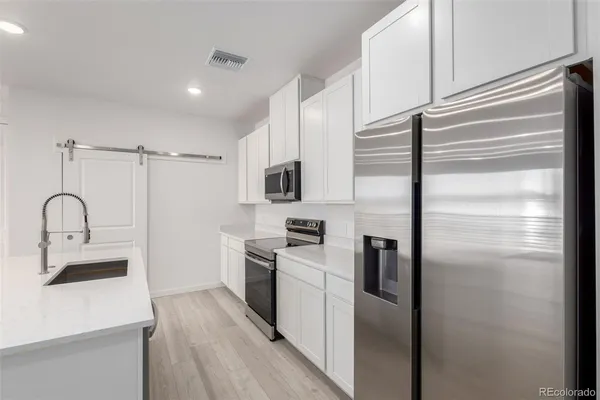 a kitchen with a refrigerator sink and cabinets