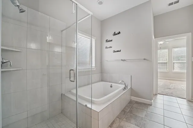 a bathroom with a tub a window and a glass door shower