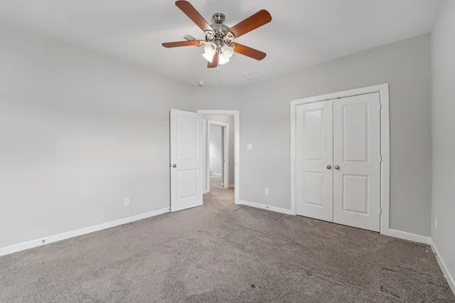 an empty room with windows and fan