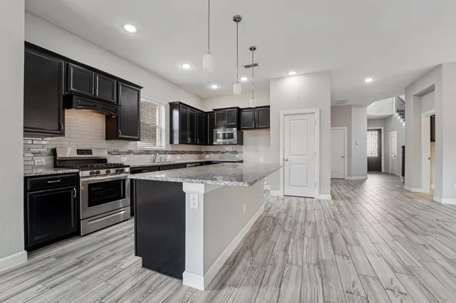 a large kitchen with stainless steel appliances granite countertop a stove a sink and a microwave