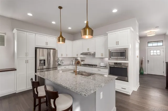 a kitchen with stainless steel appliances granite countertop a kitchen island hardwood floor sink and stove