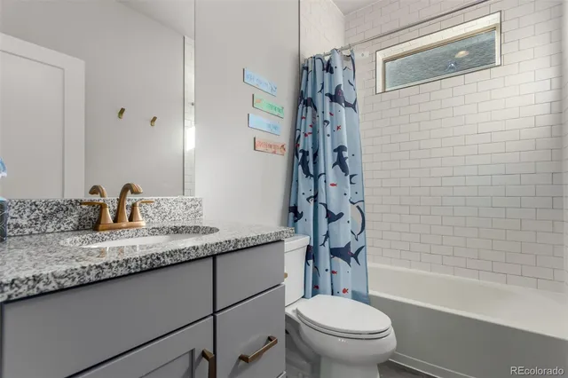 a bathroom with a granite countertop sink a toilet and a bathtub