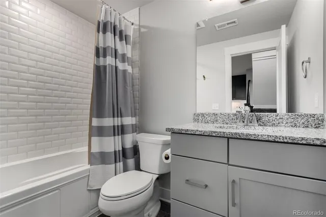 a bathroom with a granite countertop sink toilet and shower