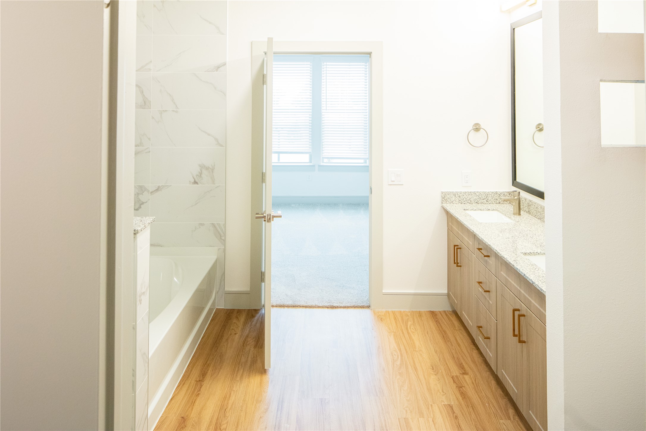 3100 Scofield Ridge Parkway, Unit 1217 Austin, TX 78727 - Photo 6 of 21 Full bathroom featuring a washtub, a sink, wood finished floors, baseboards, and double vanity