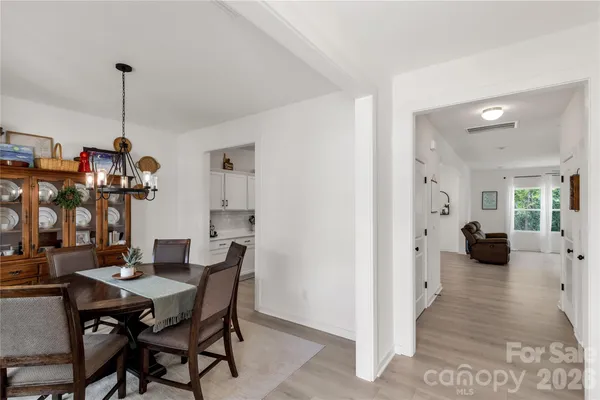 a view of a dining room and livingroom with furniture wooden floor a chandelier