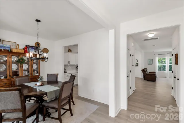 a view of a dining room and livingroom with furniture wooden floor a chandelier