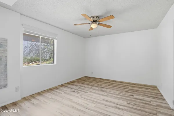 a view of empty room with wooden floor and fan