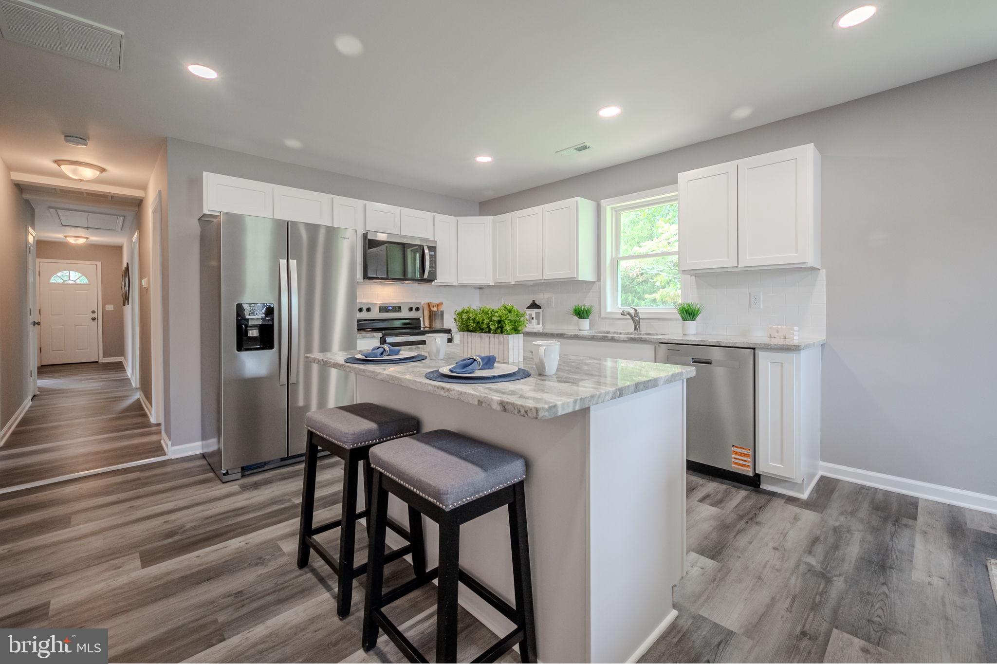 23110 Old Fairlee Road Chestertown, MD 21620 - Photo 9 of 29 a kitchen with kitchen island a stove a refrigerator and a dining table with wooden floor