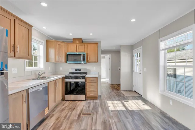 a kitchen with stainless steel appliances granite countertop wooden floors a stove a sink and a window