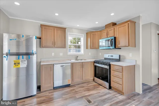 a kitchen with stainless steel appliances granite countertop a refrigerator a stove top oven a sink and dishwasher with wooden floor