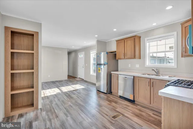 a view of a kitchen with a sink dishwasher a refrigerator and wooden cabinets