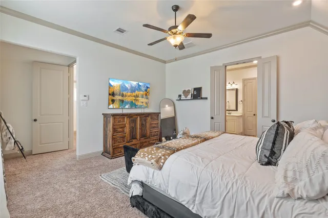 a bedroom with a bed a dresser and a chandelier