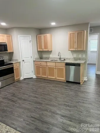 a large kitchen with granite countertop a stove top oven a sink a counter space and cabinets