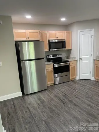 a view of kitchen with stainless steel appliances wooden floor and window