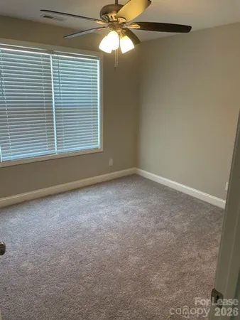 a view of empty room with window and ceiling fan