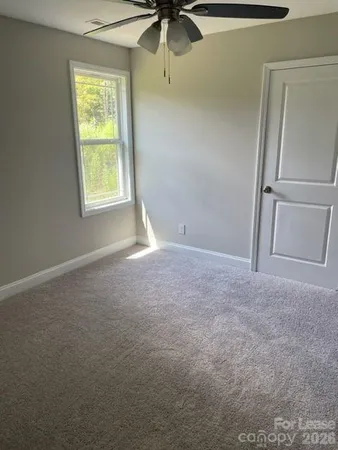 an empty room with a window and a ceiling fan