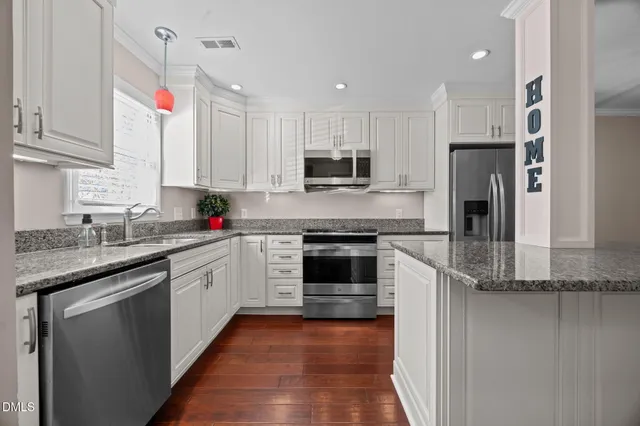 a kitchen with kitchen island granite countertop a sink cabinets and stainless steel appliances
