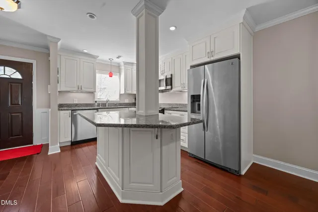 a kitchen with kitchen island granite countertop wooden floors and refrigerator