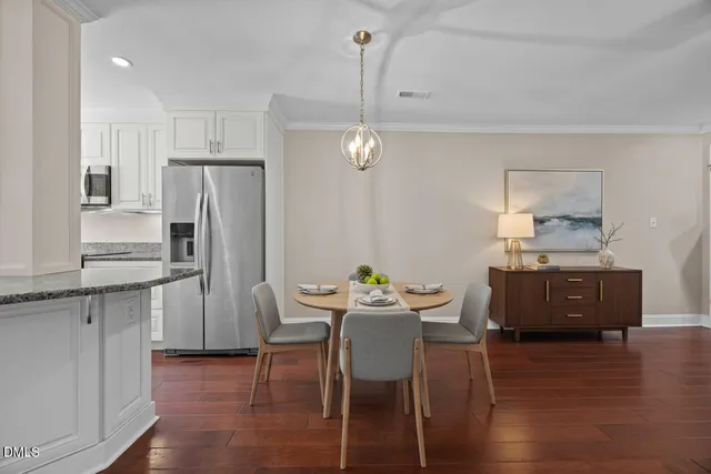 a kitchen with stainless steel appliances a dining table chairs refrigerator and sink