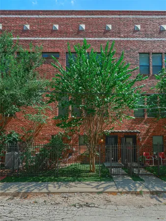 a view of a brick house with a yard and large tree