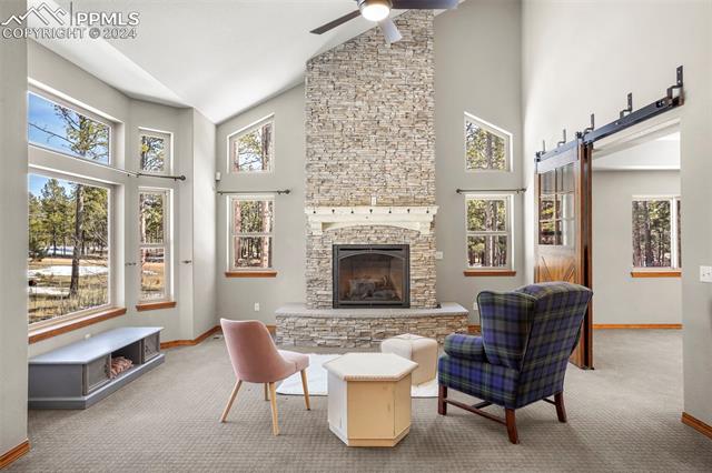 10115 Shoup Road Colorado Springs, CO 80908 - Photo 2 of 11 Carpeted living room featuring a fireplace, high vaulted ceiling, and ceiling fan