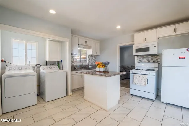 a kitchen with stainless steel appliances granite countertop a stove a refrigerator and white cabinets