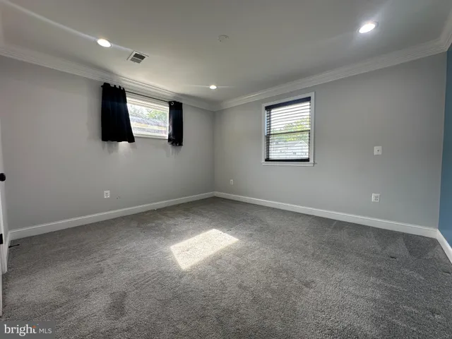 a view of an empty room with wooden floor and windows