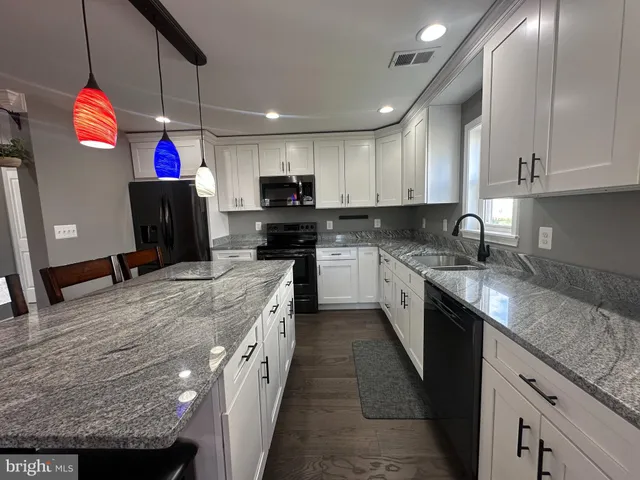 a kitchen with granite countertop a sink a counter top space cabinets and stainless steel appliances