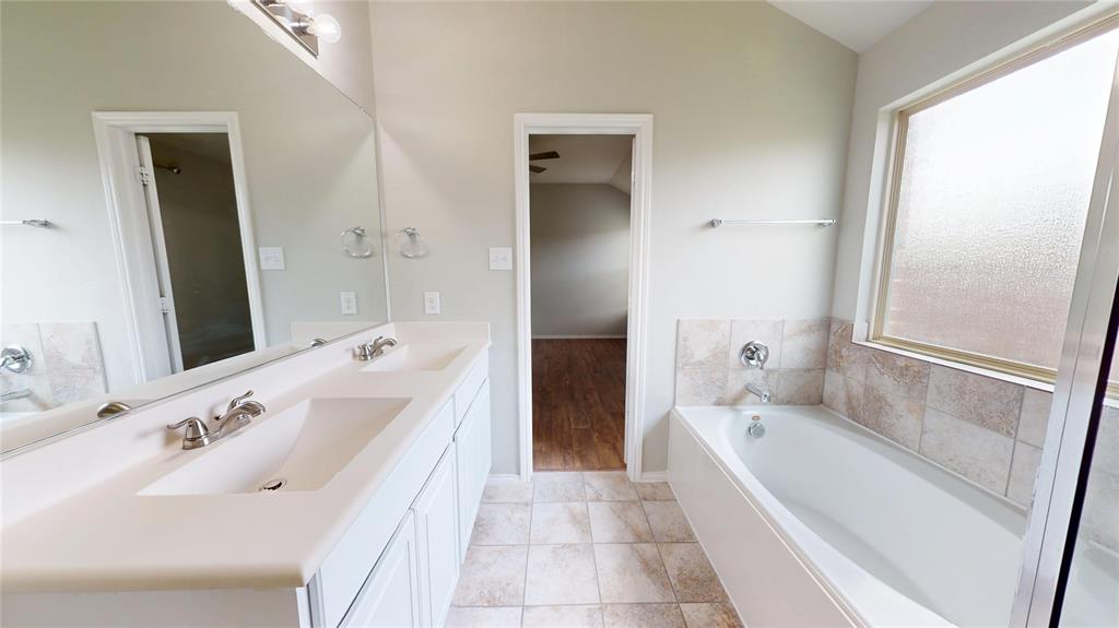 3101 Buckthorn Street Forney, TX 75126 - Photo 17 of 40 Bathroom featuring a double vanity with integrated sinks, a full-width mirror, tile flooring, and a bathtub with a tiled surround