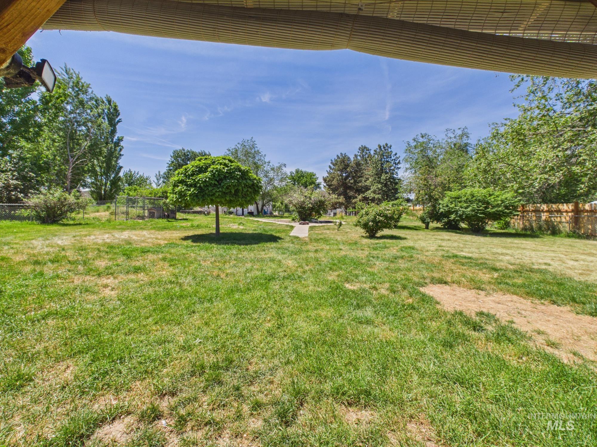 1527 North Plaza Road Emmett, ID 83617 - Photo 33 of 33 Expansive green space featuring a variety of mature trees and shrubs, a defined walking path, and a wooden perimeter fence