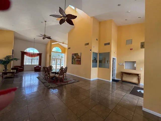 a living room with couches a dining table and a chandelier with kitchen view