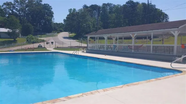 a view of pool with lawn chairs and wooden fence