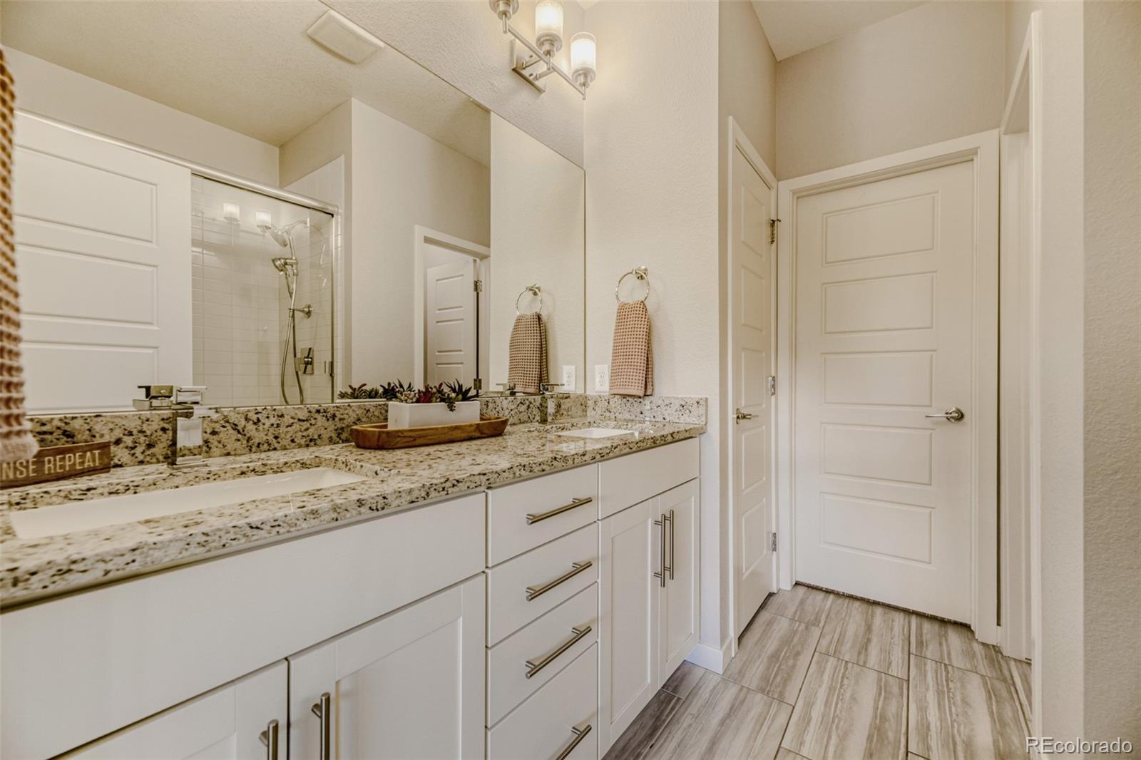 11691 West 45th Place Wheat Ridge, CO 80033 - Photo 15 of 30 a bathroom with a granite countertop sink two mirror and a shower