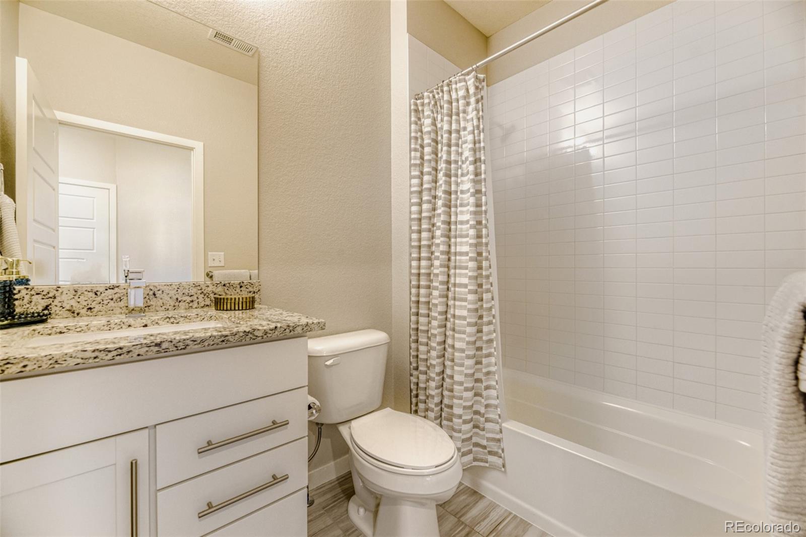 11691 West 45th Place Wheat Ridge, CO 80033 - Photo 21 of 30 a bathroom with a granite countertop toilet a sink and a bathtub