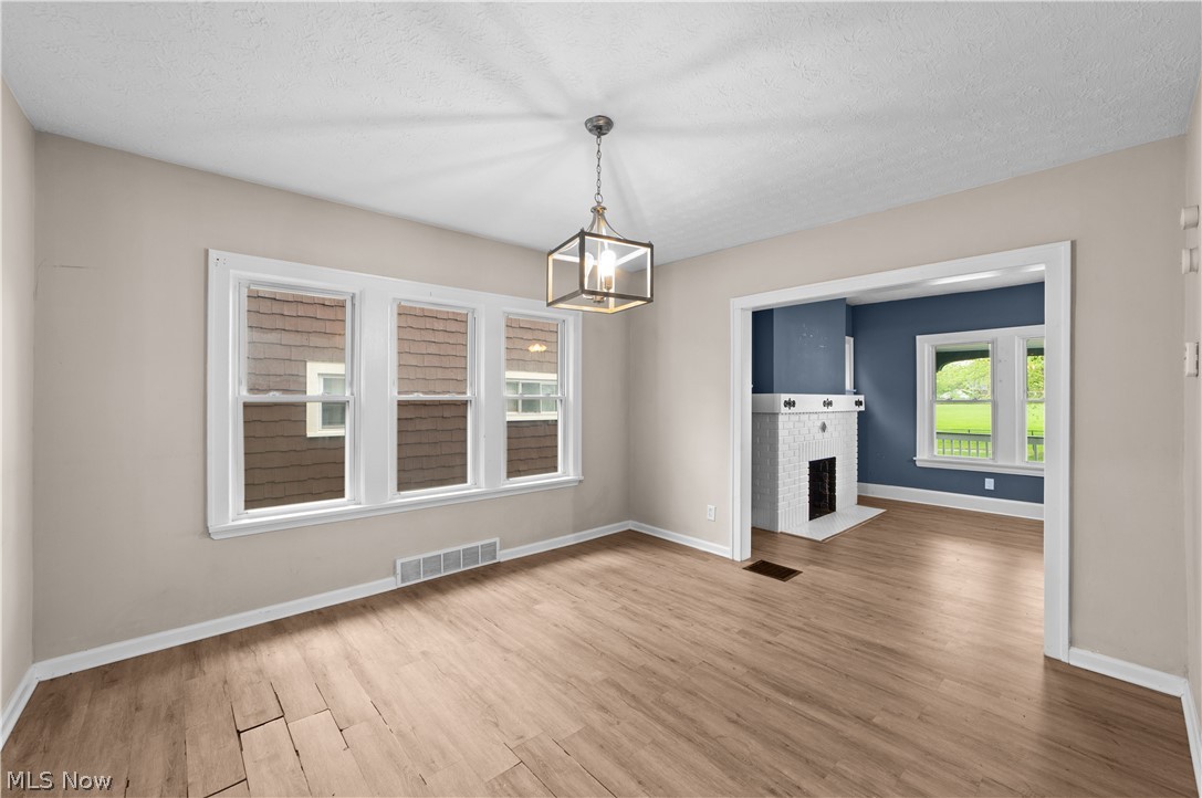 1062 Yellowstone Road Cleveland Heights, OH 44121 - Photo 8 of 29 Spare room with a chandelier, a textured ceiling, hardwood / wood-style floors, and a fireplace